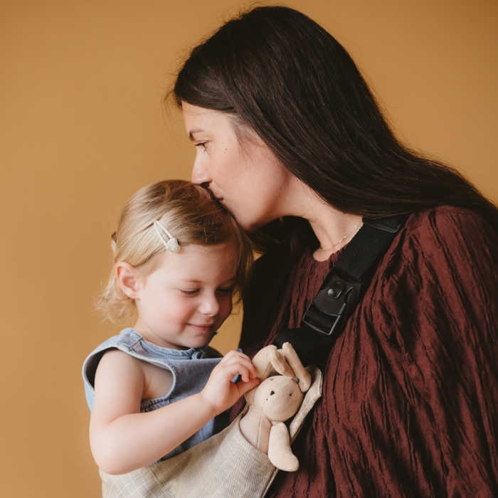 Woman carrying a child in the Grid hip baby carrier